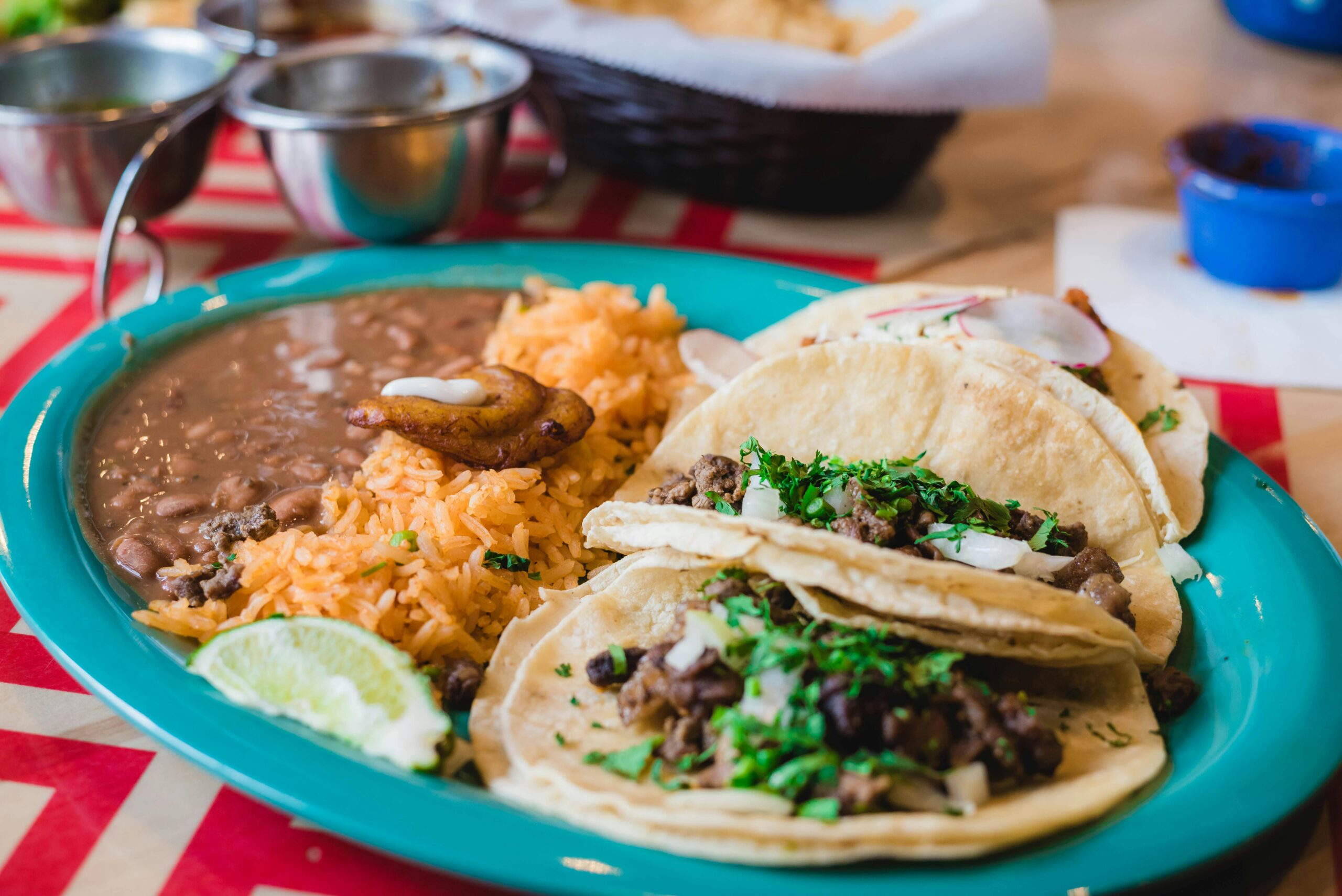 Mouth-watering Mexican tacos served with rice and beans, garnished with cilantro and lime.